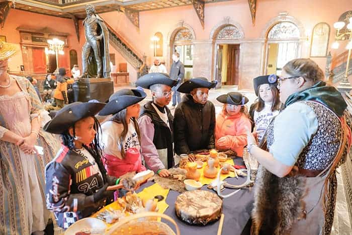Children gather around a table for an interactive colonial history demonstration.